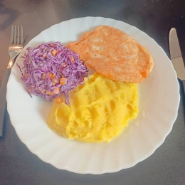 Kotlet z kurczaka oraz puree i surówką z czerwonej kapusty.