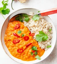 Gulasz curry z czerwonej soczewicy z ryżem i świeżą kolendrą.